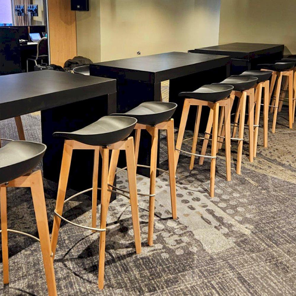 Black Tavola tables with low back Esme stools to create a chic and sophisticated reception area for guests.